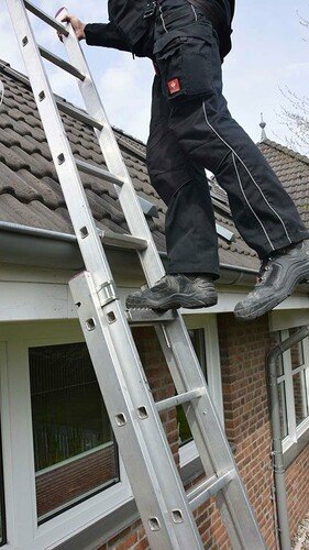 Einsatzfoto eines Dacharbeiter, der über eine gesicherte Leiter das Steildach betritt.