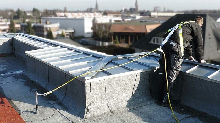 Employé travaillant en bordure de toit attaché à un ancrage de protection antichute ABS-Lock III-BE