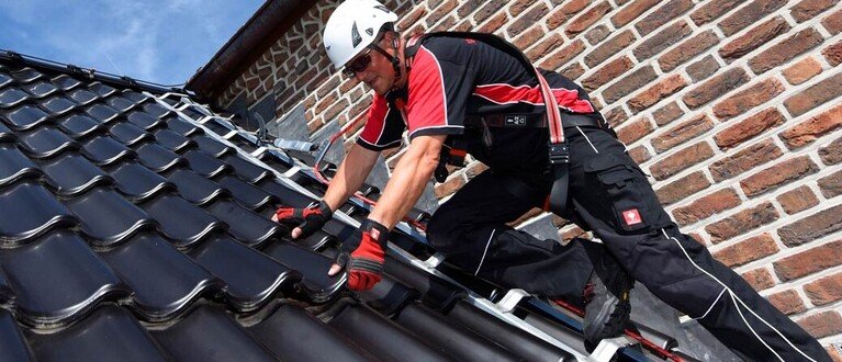 Dachdecker auf einem Steildach gesichert an einem ABS Dachhaken