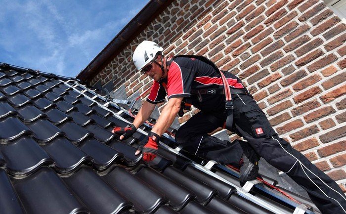 Roofer on a pitched roof surface - secured using an ABS roof safety hook