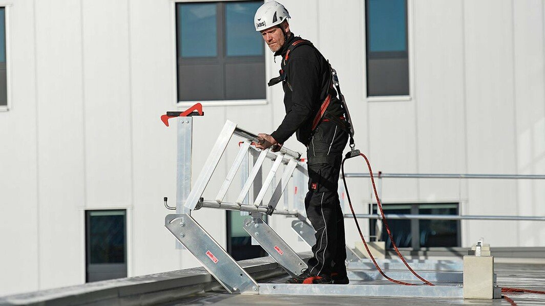 Einsatzfoto eines Höhenarbeiters, der das Geländer eines mobilen Geländers ausklappt.